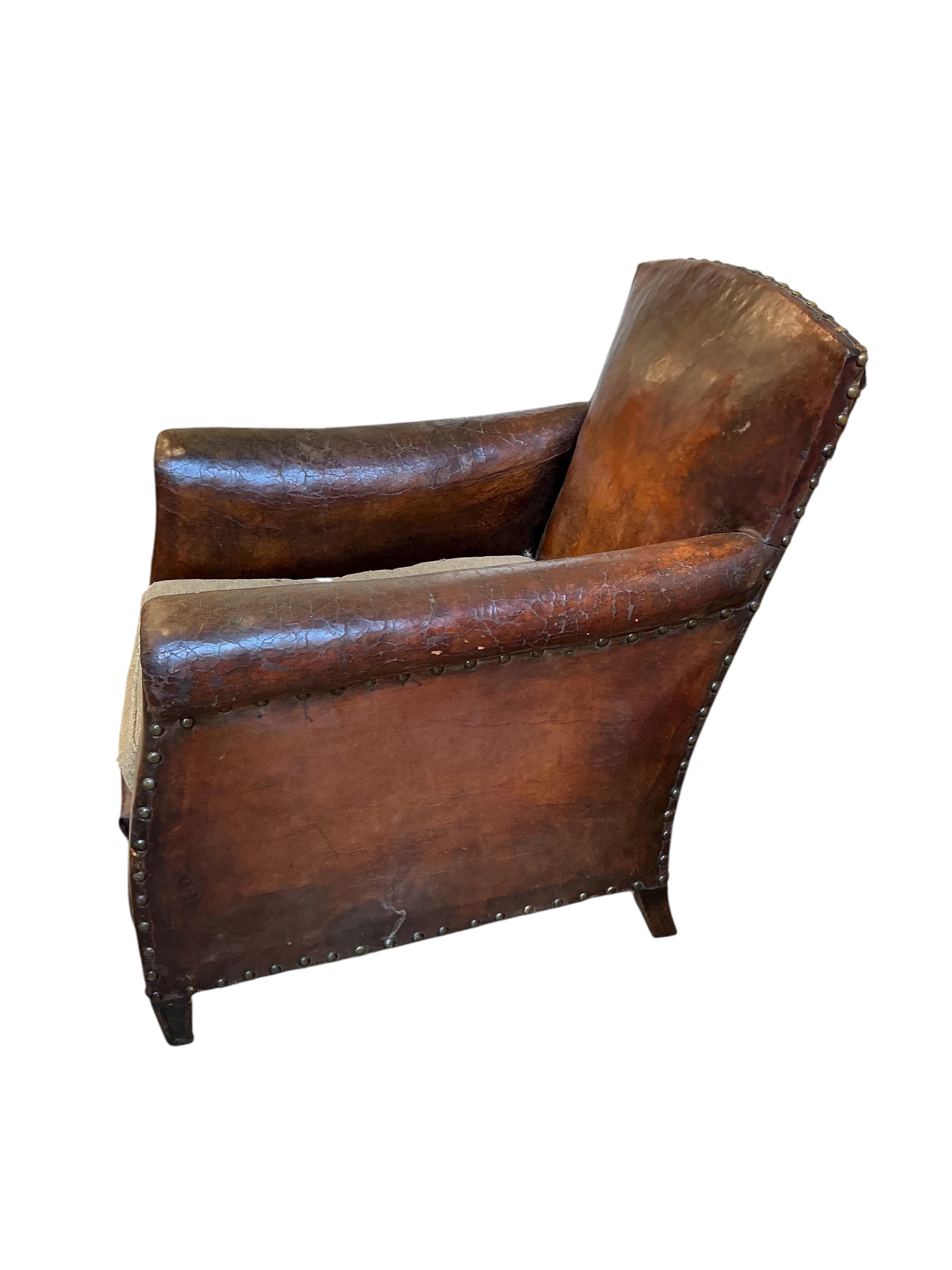 A near pair of early 20th century studded brown leather club chairs, width 79cm, depth 86cm, height 89cm